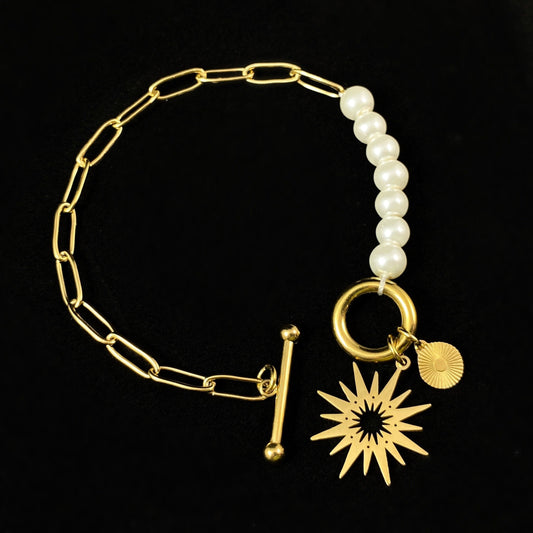 White Pearl Bracelet with Gold Sunburst Accent, a Chunky Gold Chain, and a Decorative Toggle Clasp