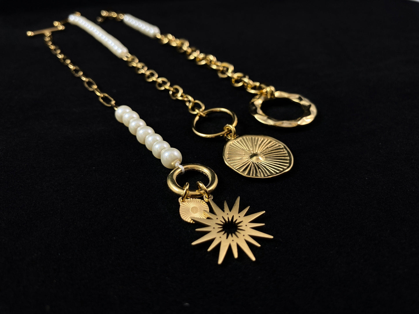 White Pearl Bracelet with Gold Sunburst Accent, a Chunky Gold Chain, and a Decorative Toggle Clasp