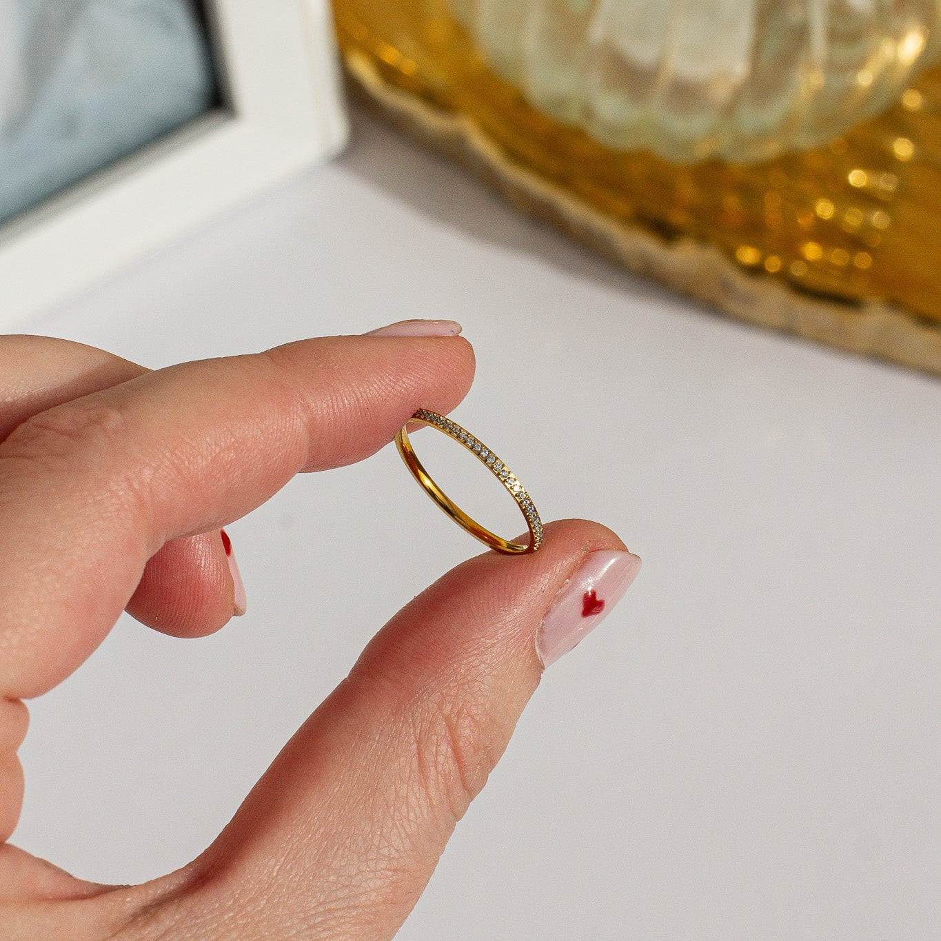 Hand holding a gold ring with a blurred decorative background