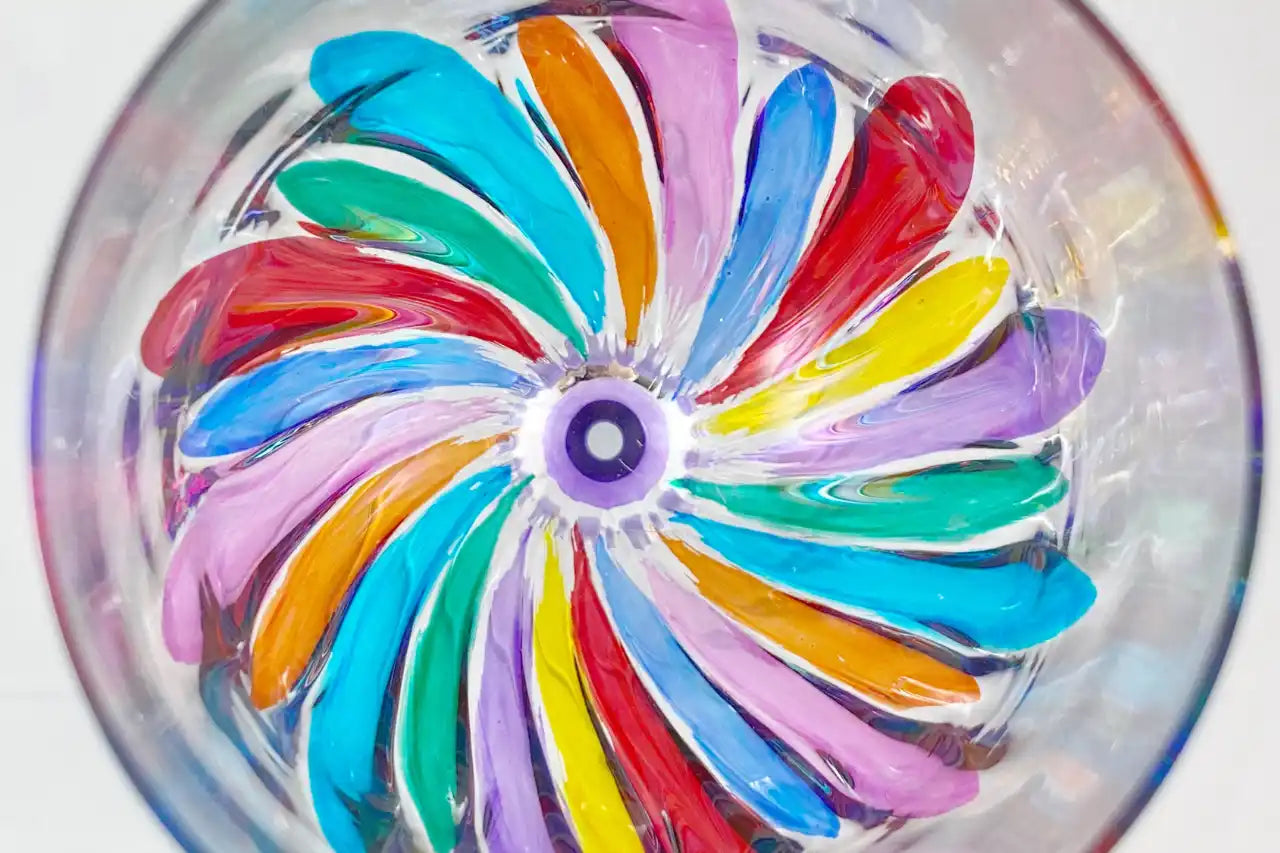 Colorful pinwheel pattern made of swirling painted segments radiating from a central purple point.