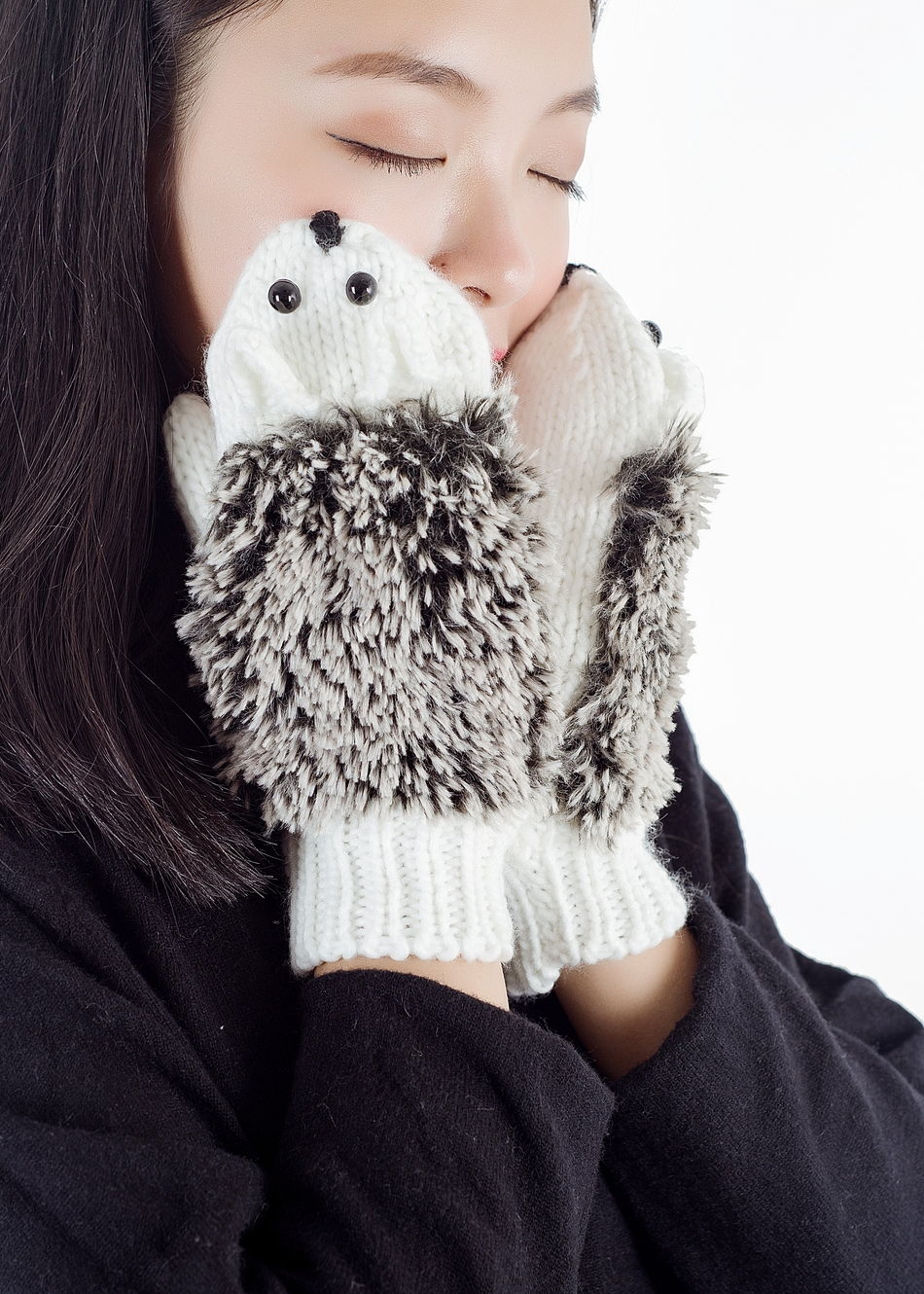 Person wearing fluffy hedgehog mittens on a white background