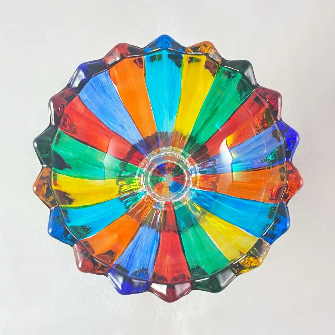 A vibrant, multi-colored glass bowl with a scalloped edge and a central starburst pattern.