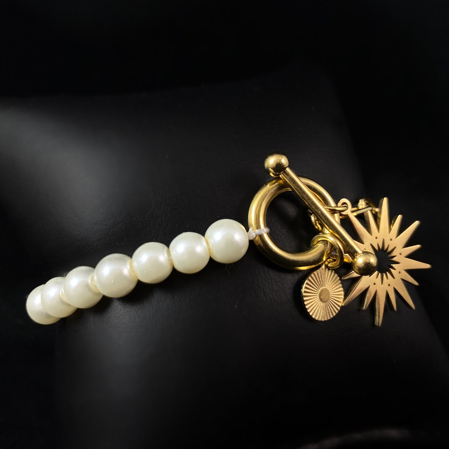 White Pearl Bracelet with Gold Sunburst Accent, a Chunky Gold Chain, and a Decorative Toggle Clasp